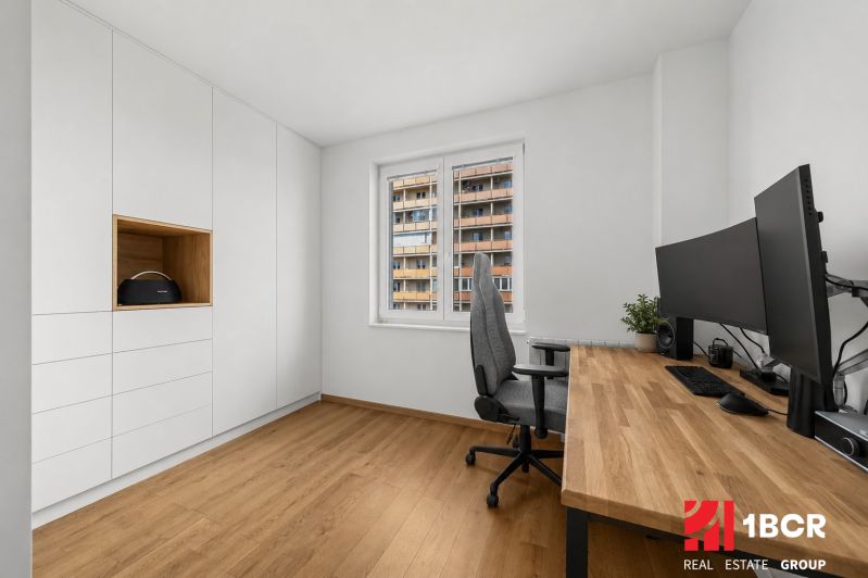 A study in a 3-room apartment with a wood-patterned floor, white cabinets, and a desk.