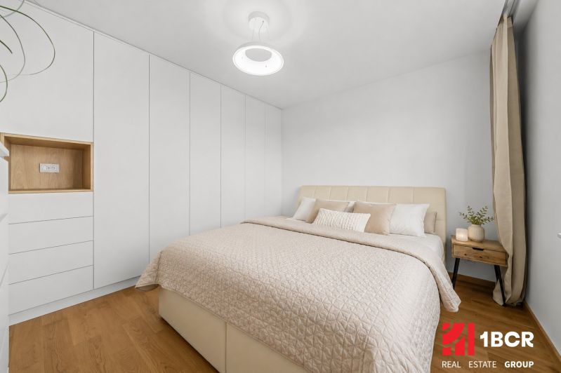 A bright bedroom with a bed, built-in wardrobes, and a wooden decor floor in a 3-room apartment.