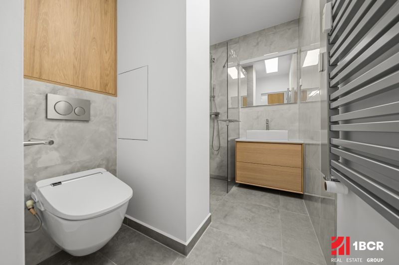 Bathroom in a 3-room apartment with a shower, sink, and wall-mounted toilet with a wood decor.