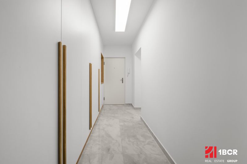 A bright hallway with white walls and tiles in a 3-room apartment.