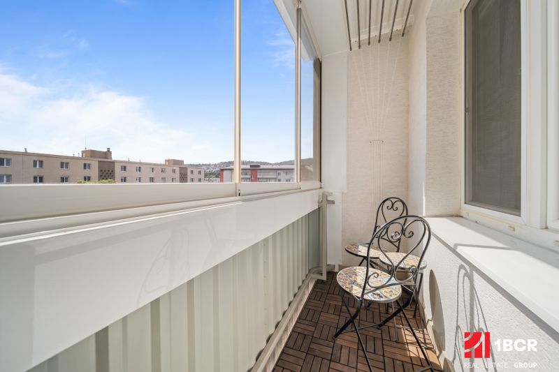 Glazed balcony with wooden floor decor in a 3-room apartment with a table and chairs.