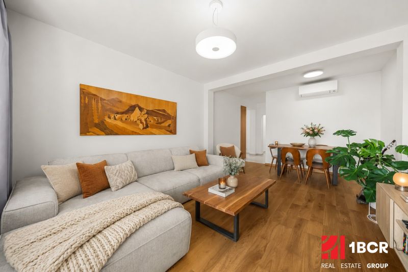Living room in a 3-room apartment, sofa, table, and floor with wooden decor.
