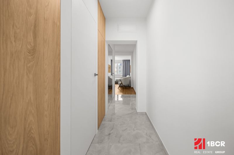 A hallway with white walls and a wooden decor floor in a 3-room apartment.