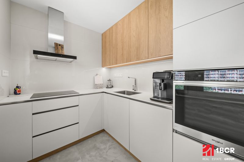 A kitchen in a 3-room apartment with white cabinets and built-in appliances.