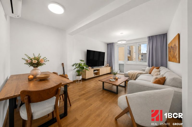 Living room in a 3-room apartment with a wooden decor floor, light furniture, and decorations.