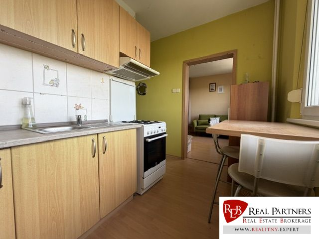 A kitchen in a studio apartment with a wooden decor floor, dining table, and equipment.