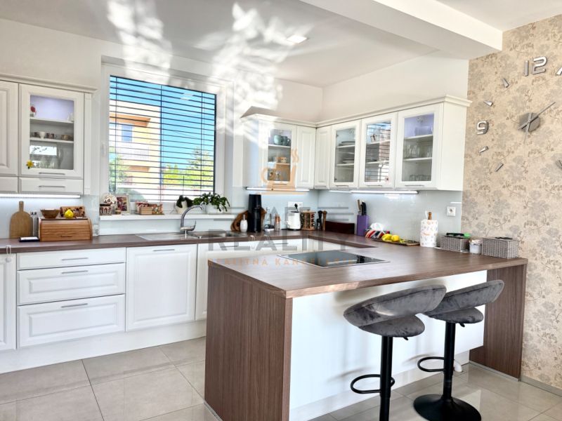 A kitchen in a family house with white cabinets, a coffee counter, and a clock on the wall.