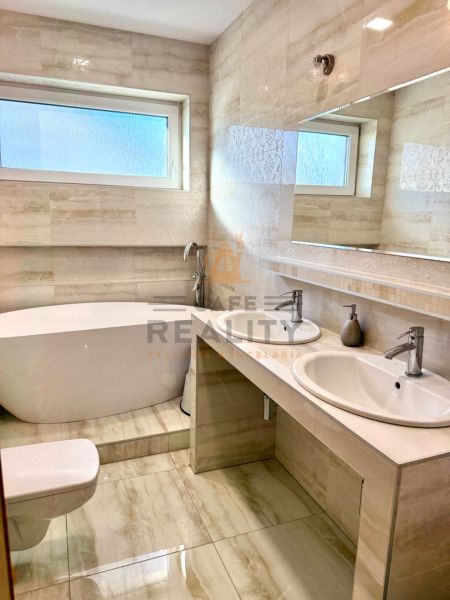 A bathroom in a family house with a bathtub, shower, and sink with storage space.