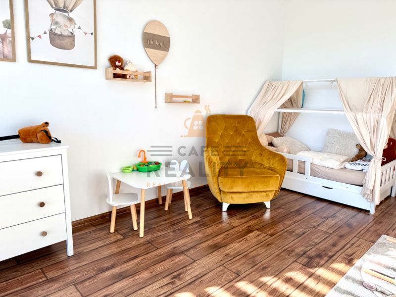 Children's room in a family house with a wooden decor floor, bed, chair, and toys.