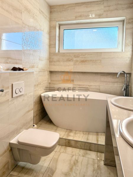 A bathroom in a family house with a bathtub, toilet, and double sink.