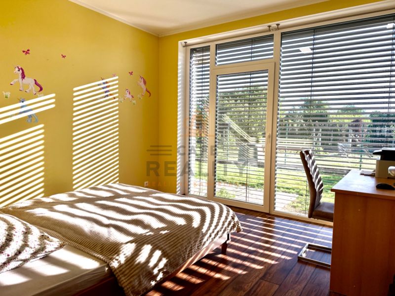 Children's room with unicorns, a large window, and a wooden decor floor in a family house.