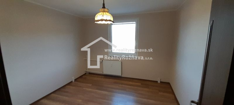 A room in a 2-room apartment with a wood-decor floor and a light above the radiator.