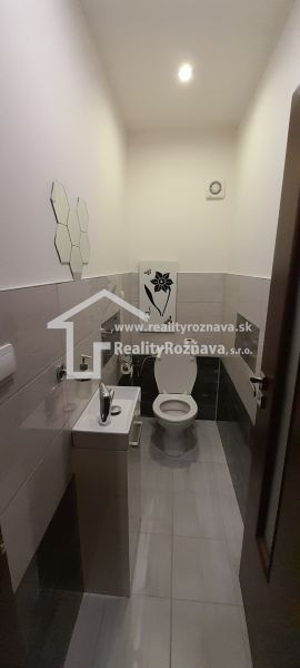 Bathroom in a 2-room apartment with a toilet, sink, and light tiles.
