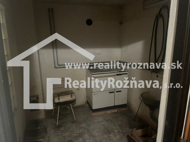 A small room with a kitchen stove, sink, and concrete floor, suitable for a cabin.