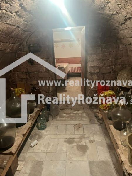 A traditional stone cellar in a cottage with shelves and demijohns.