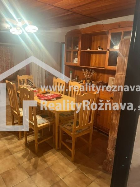 Dining area in a cabin with a wooden table and chairs, illuminated by a chandelier.