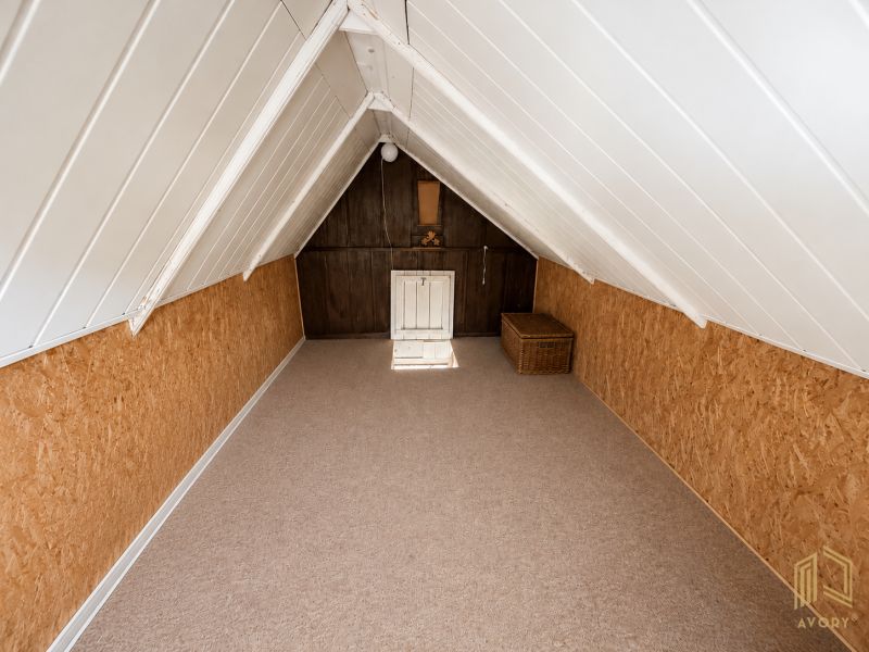 The attic of the cottage with wooden decor and a rattan storage basket.