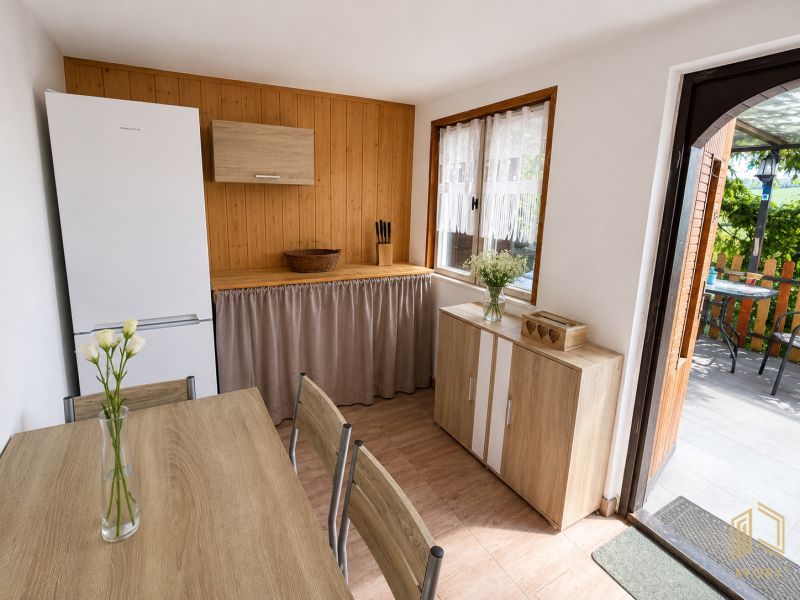A kitchen in a cottage with a wooden decor floor, a table, and white flowers.