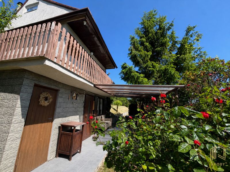 A cottage in Kunov near Senica surrounded by greenery and flowers with wooden elements.