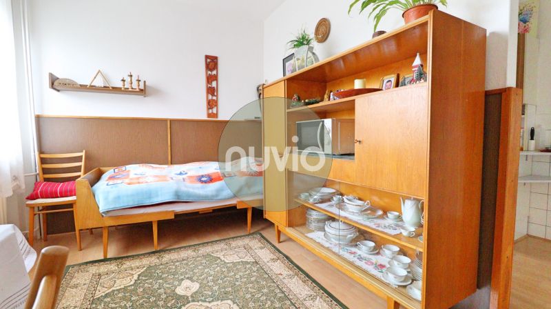 A room in a family house with a bed, retro furniture, and shelves with porcelain.