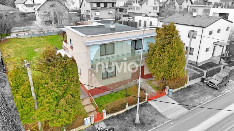 A two-story family house in Martin with a garden, surrounded by trees and a fence.