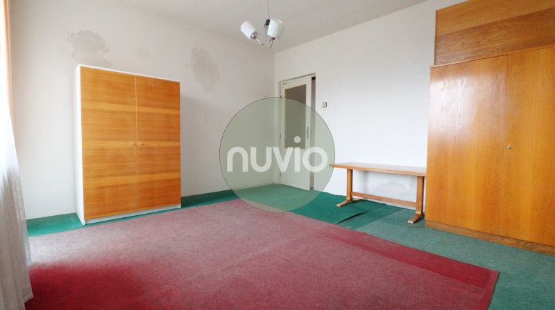 An empty room in a family house with furniture and a green carpet.