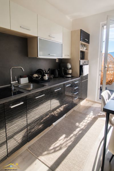 A kitchen in a 2-room apartment with dark cabinets and a wood-patterned floor.