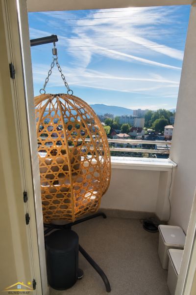A balcony in a 2-room apartment with a rattan chair and a view of the city.