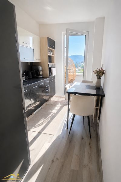 A kitchen in a 2-room apartment with a wooden decor floor and a view of the exterior.