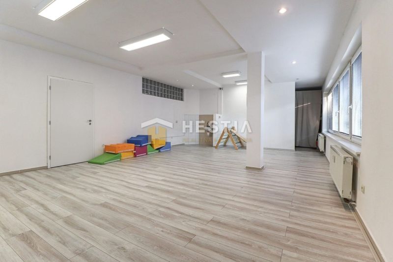 Commercial spaces with wood-patterned flooring, ceiling lighting, colorful mattresses, and windows.