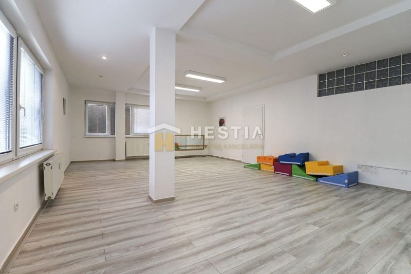 Spacious commercial spaces with wood-patterned flooring and colorful seating elements.
