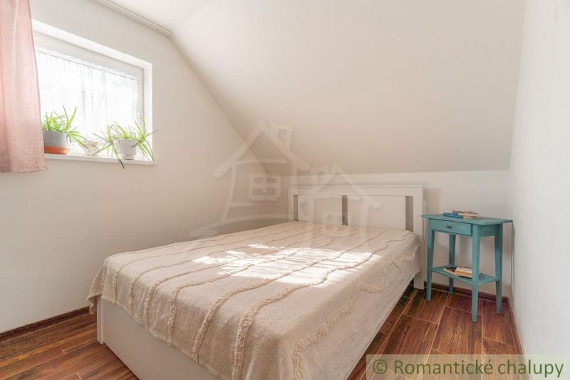 Bedroom in a family house with a bed, nightstand, and floor with wooden decor.