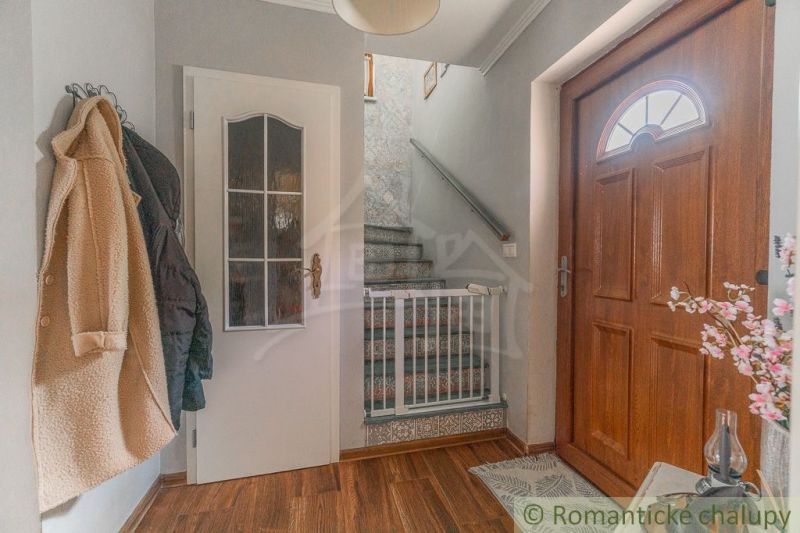 Entrance hall with wooden doors, wood-patterned flooring, and staircase in a family house.