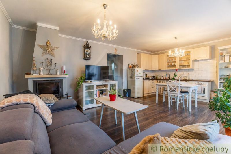 Living room in a family house with a fireplace, kitchen, and wooden decor flooring.