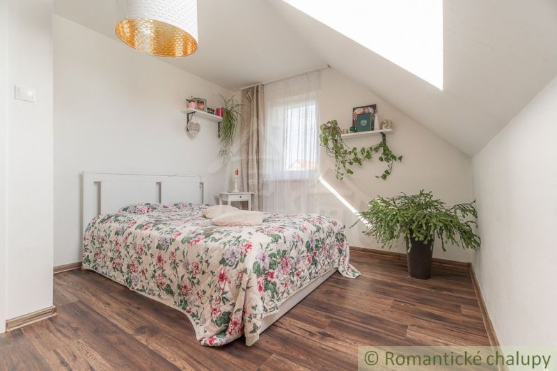 A bright bedroom in a family house with a wood-patterned floor and plants.
