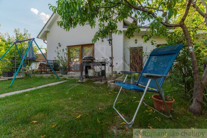 The garden of a family house in Bernolákovo with a swing, garden furniture, and greenery.
