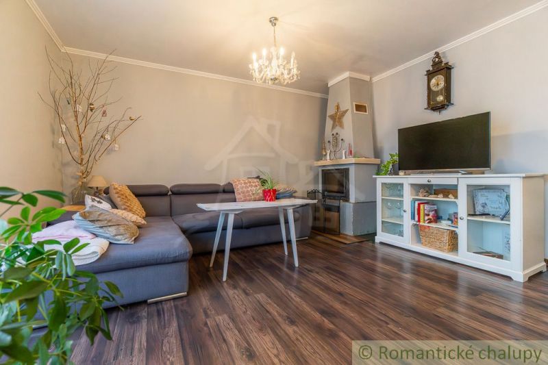 Living room in a family house with a fireplace, corner sofa, and wooden decor flooring.