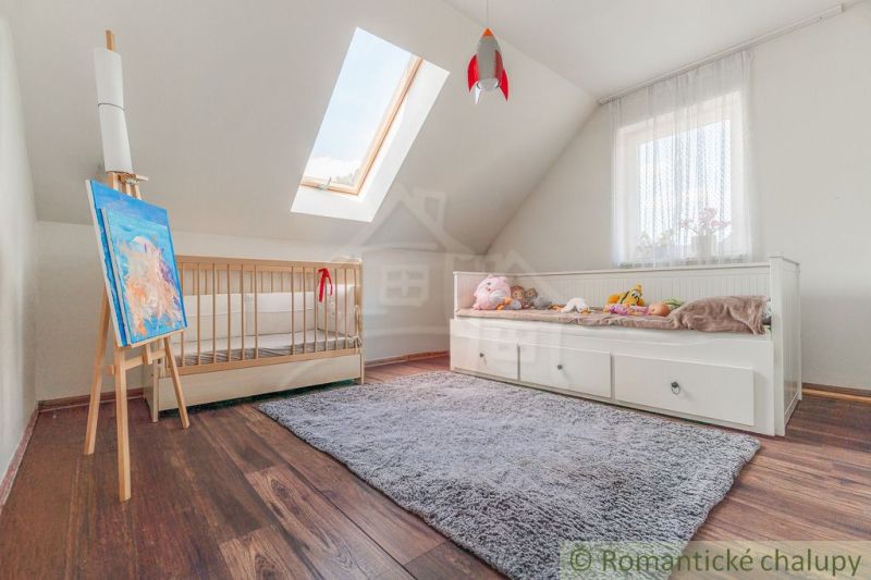 Children's room with a bed, wooden decor, and a skylight in a family house.