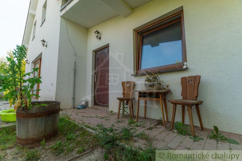 The exterior of a family house in Bernolákovo with a terrace and wooden furniture.