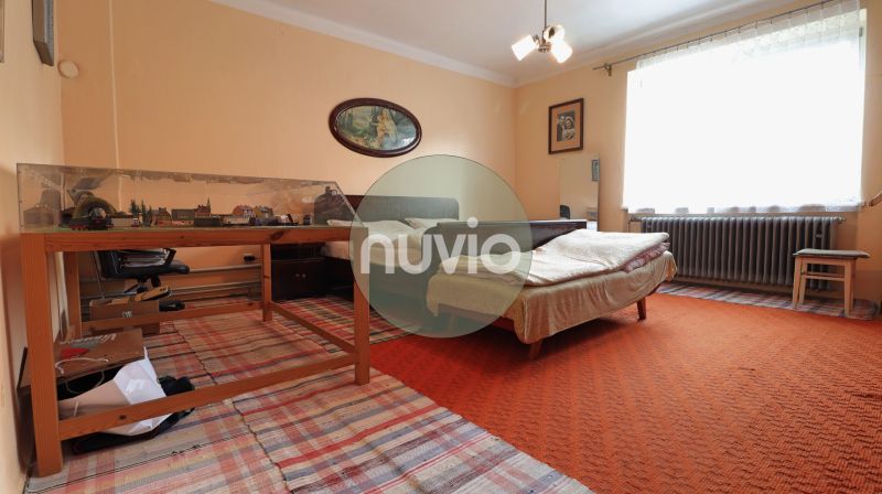 A bedroom with a light orange carpet and a model railway in a family house.