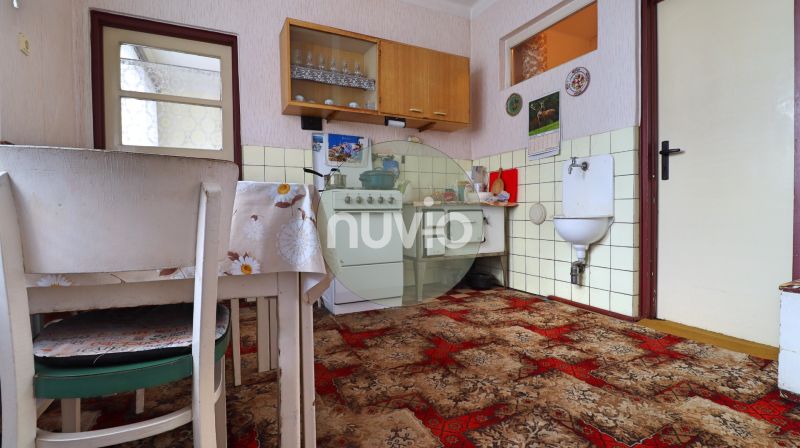 A kitchen in a family house with a carpet, dining table, and gas stove.
