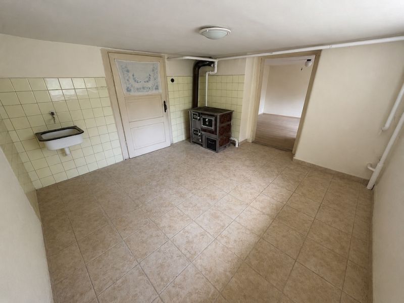 A kitchen in a family house with tiles and a sink, floor with wood decor.