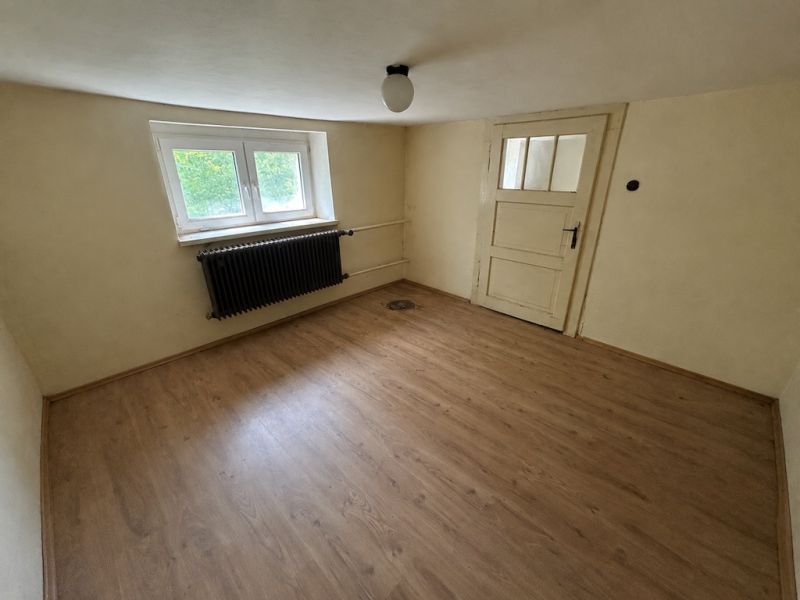 A room in a family house has a wooden decor floor and white walls.
