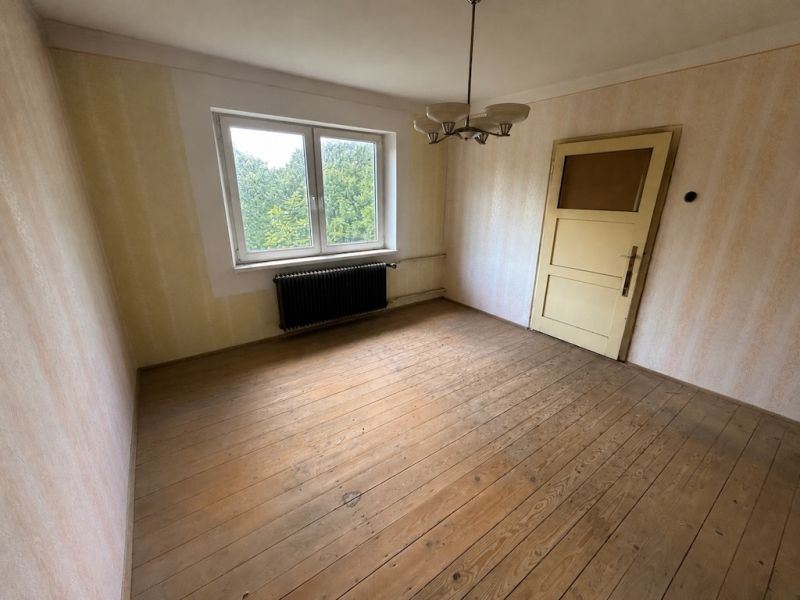 A room in a family house with a wooden decor floor and a large window.