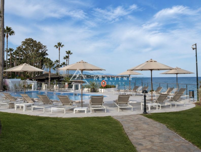 A pool with loungers and palm trees by the beach at Dominion Beach in Estepona.