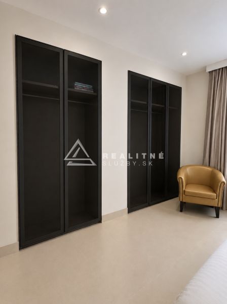 In the 4-room apartment, there is a black wardrobe and a beige armchair.