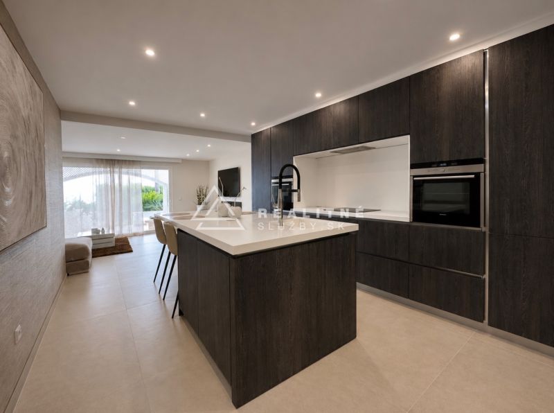 A kitchen in a 4-room apartment with dark cabinets and an open space to the living room.
