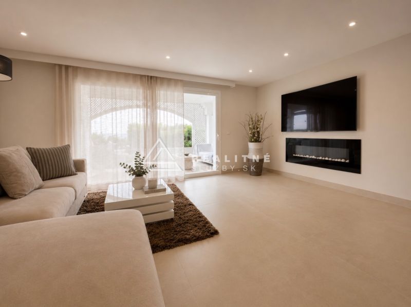 Living room of a 4-room apartment with a comfortable sofa and a TV on the wall.