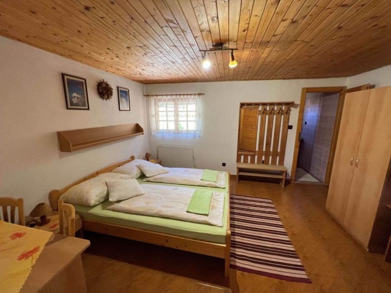 A room in a family house with wooden decoration and a bed, carpet, wardrobe, and window.