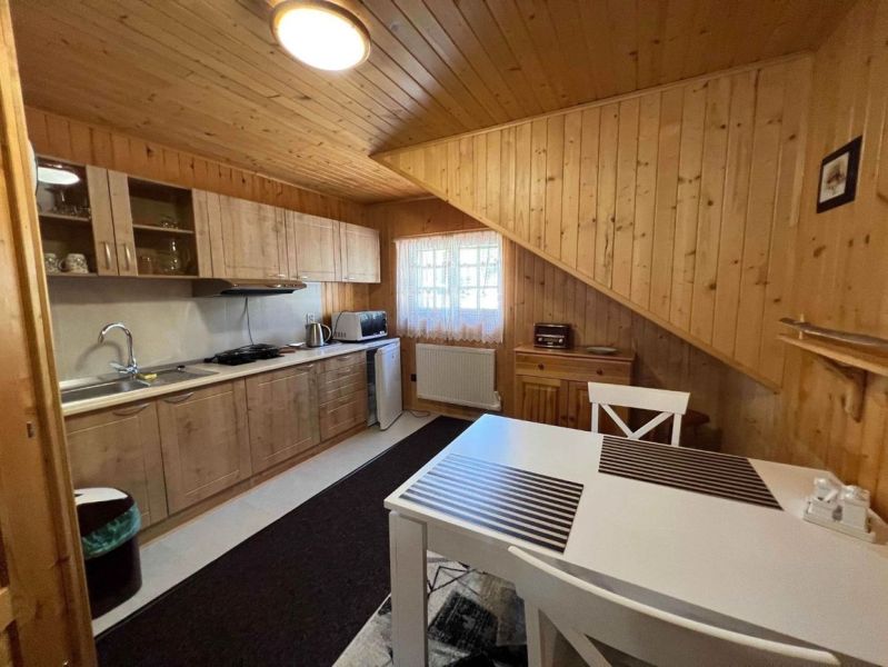 A kitchen in a family house with wooden paneling, a white table, and a countertop.